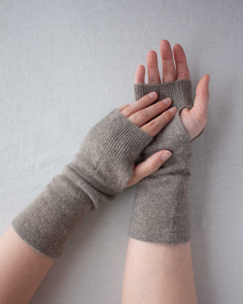 Two hands wearing grey cashmere fingerless gloves