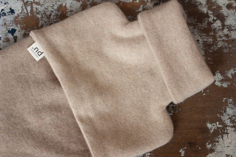 Beige cashmere hot water bottle covered on textured background