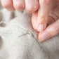 Close-up of hands mending a cashmere jumper.