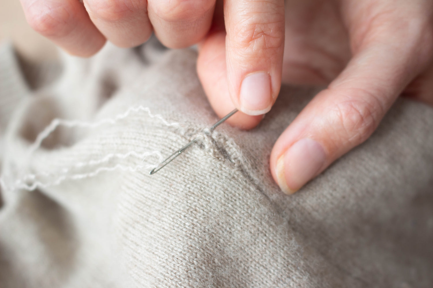 Hand mending cashmere with a needle and yarn