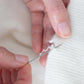 Hands mending a white cashmere jumper