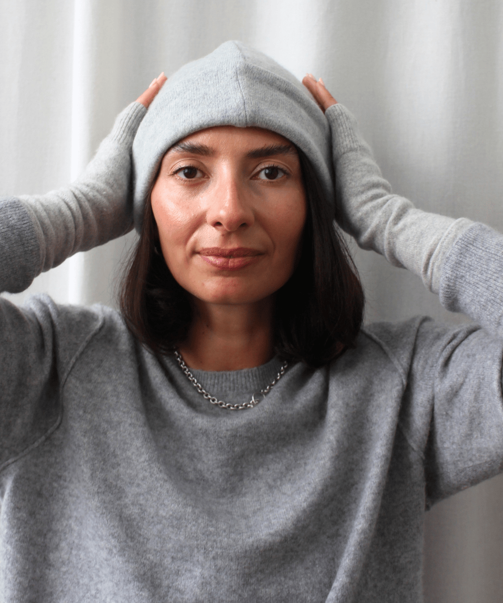 Woman wearing reclaimed cashmere beanie hat and cashmere fingerless gloves.