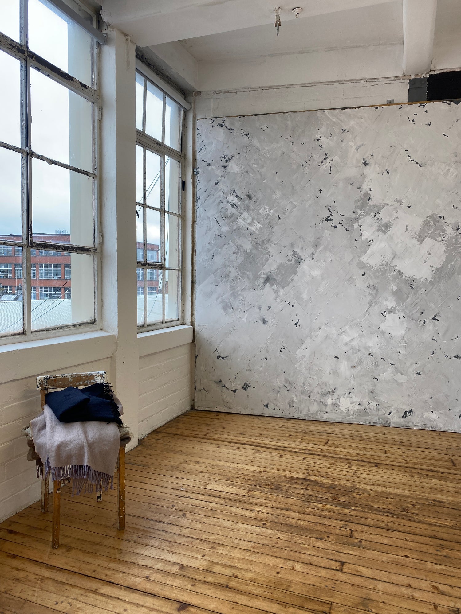Room with wooden floor, large window, and textured wall.