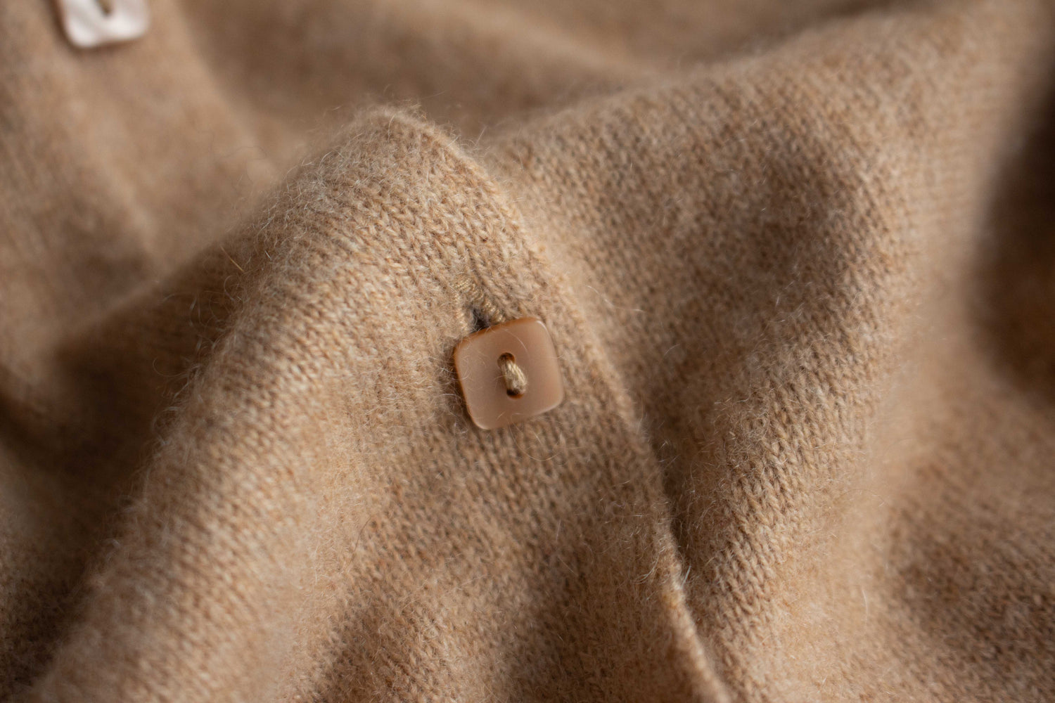 Close-up of beige cashmere fabric with a button